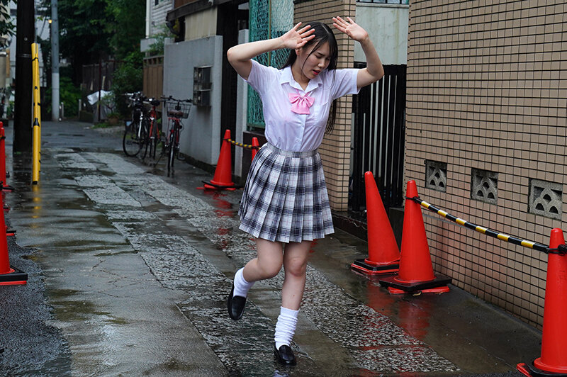 雨の路地で両手を頭に当て、チェックのスカートと白いソックスで走る制服の女性