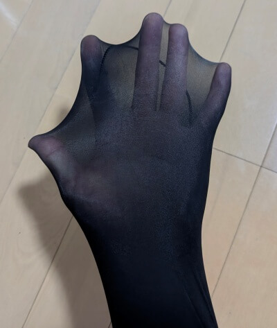 光沢パンストを手に被せ、その目の細かさとしなやかな伸びを確かめている様子