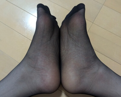 黒いオーソドックスパンストを履いた両足を揃え、つま先や足裏の透け感を強調したアップ写真